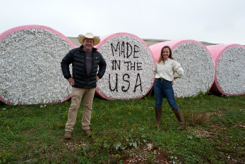 Red Land Farms owners pose on farm in front of rolls of cotton, one of which reads "Made in the U.S.A."