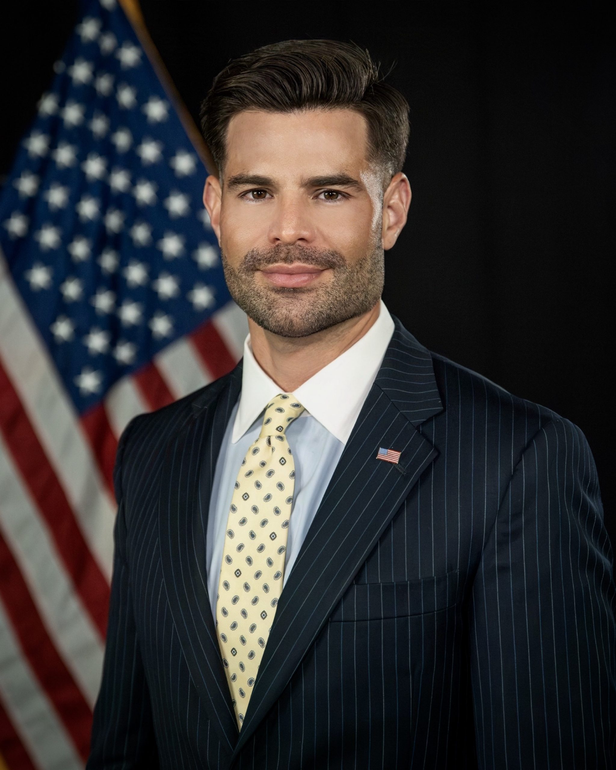 Stuart West standing in front of an American flag.